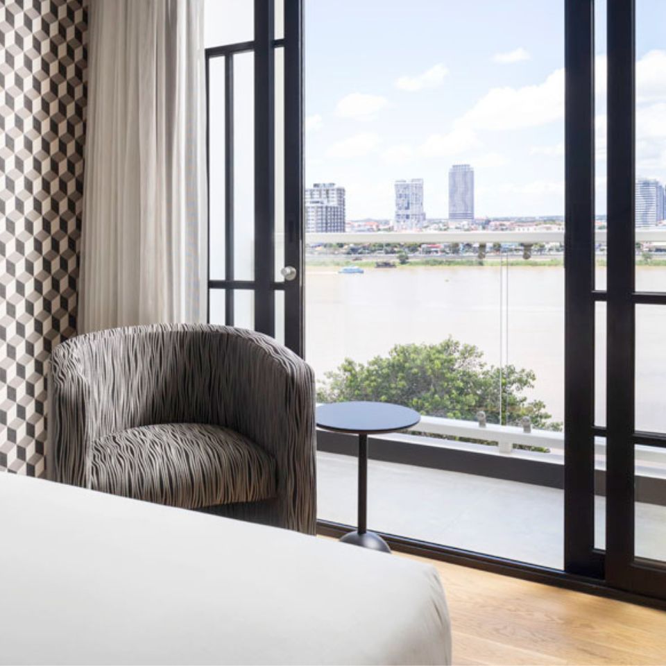 A gray armchair and a small table sit in front of a floor to ceiling window.